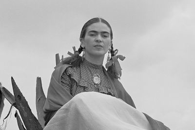 a black and white photograph of Frida Kahlo sitting next to an agave plant