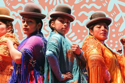 Graphic design showcasing four Bolivian cholitas in traditional attire, striking combat poses.