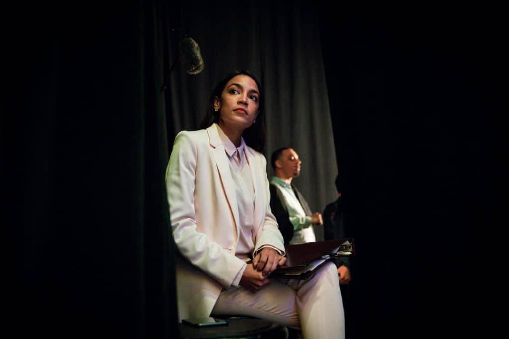 photo of woman, Alexandria Ocasio-Cortez, sitting in white suit