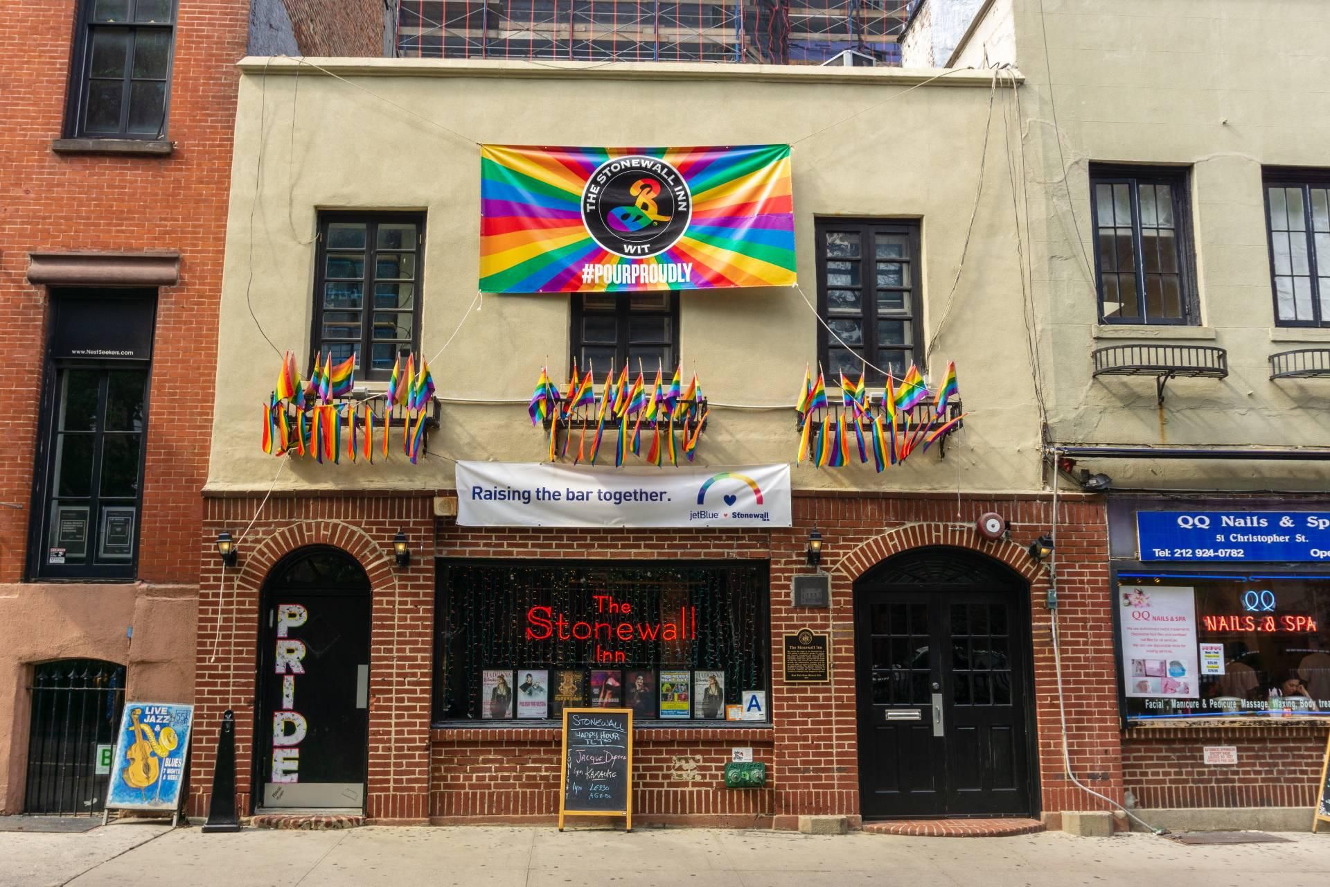 picture of the front entrance of the Stonewall Inn, adorned with rainbow pride flags