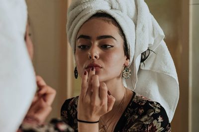 an image of a girl applying lip balm in the mirror