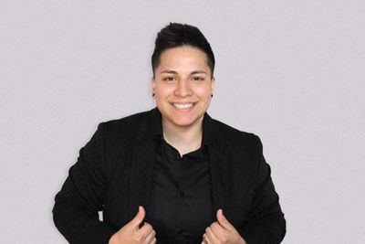 a photo of DJ KICKIT in a black blazer and top with a simple white background