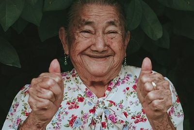 Latina grandma smiling at the camera while giving a thumbs up 