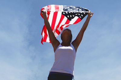 a woman holding a USA flag with the blue sky as a background