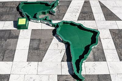 United States, Central America, and South America as large green cut outs on a concrete floor 