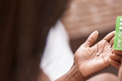 a woman hold a packet of birth control pills and a pill in her hand 