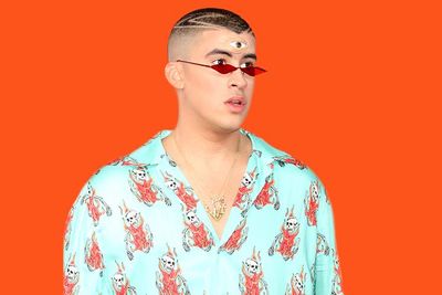 Pictured: Bad Bunny wearing a coral shirt, sunglassess and a third eye on his forehead 