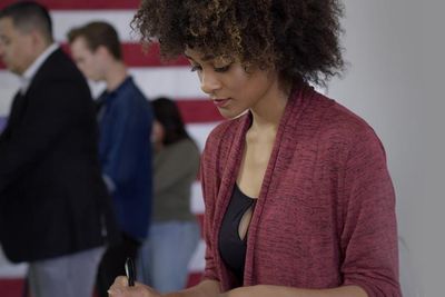 curly haired latina casting her ballot at the voting station