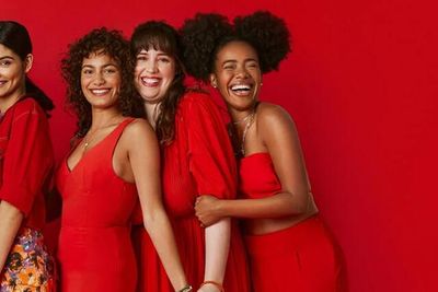 seven latina women dressed in red smile at the camera