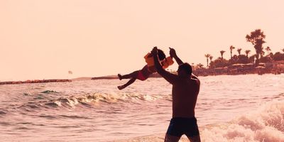 Father lifting his daughter up at the beach. 