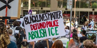 Sign that says "Black lives matter defund the police abolish ICE" 