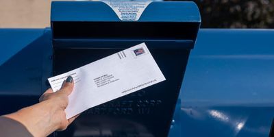 Voting mail being put in the mailbox.