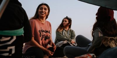 smiling woman wearing a tshirt sits cross-legged with three female friends 