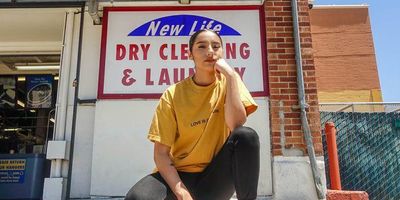 latina woman kneeling in front of a dry cleaning and laundry business