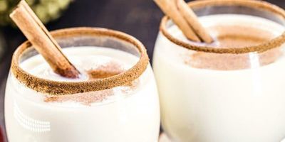 two glasses of coquito rimmed with cinnamon 