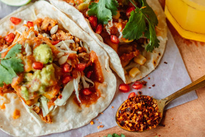 photograph of a colorful table full of fresh ingredients and 2 tacos ready to eat